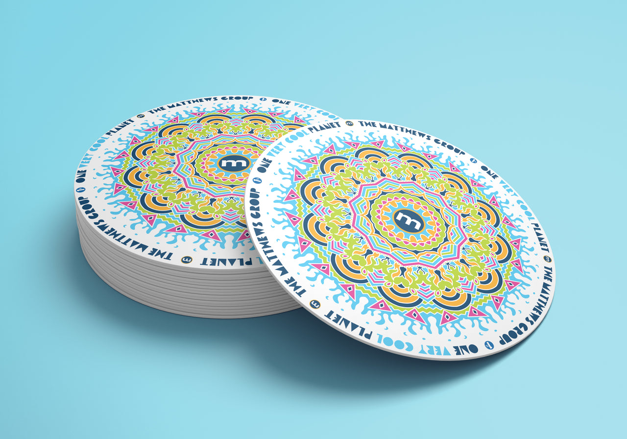 A coaster with a mandala design with "Very Cool Planet-The Matthews Group”  repeated around the parameter.