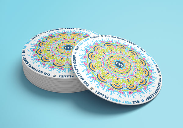 A coaster with a mandala design with "Very Cool Planet-The Matthews Group”  repeated around the parameter.