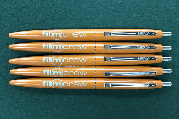 Orange click pens inscribed with: film crew, MOS click set pen. 